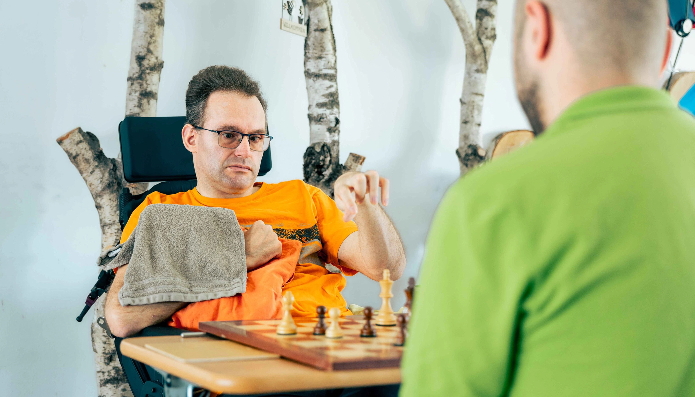 Pflegebedürftiger Mann im Rollstuhl spielt Schach zur geistigen Aktivierung