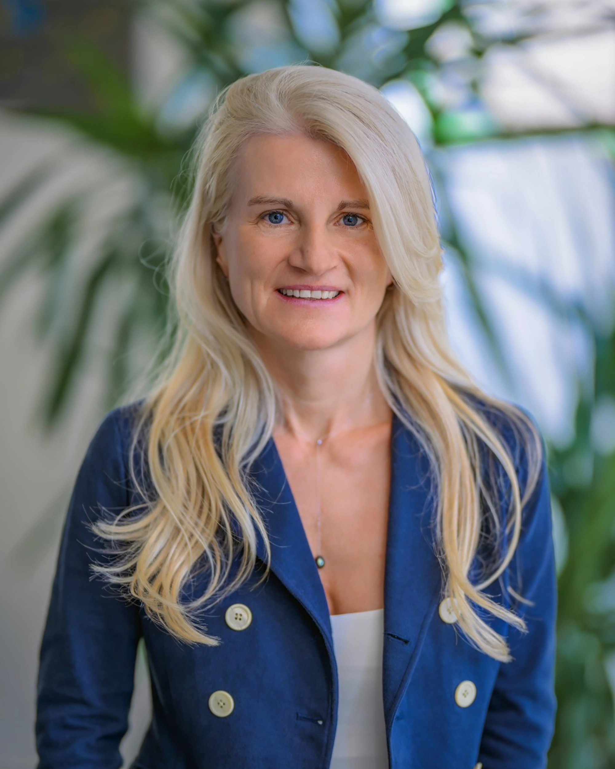 Nicole Tobias in frontalem Portrait, freundlich lächelnd in einem blauen Blazer