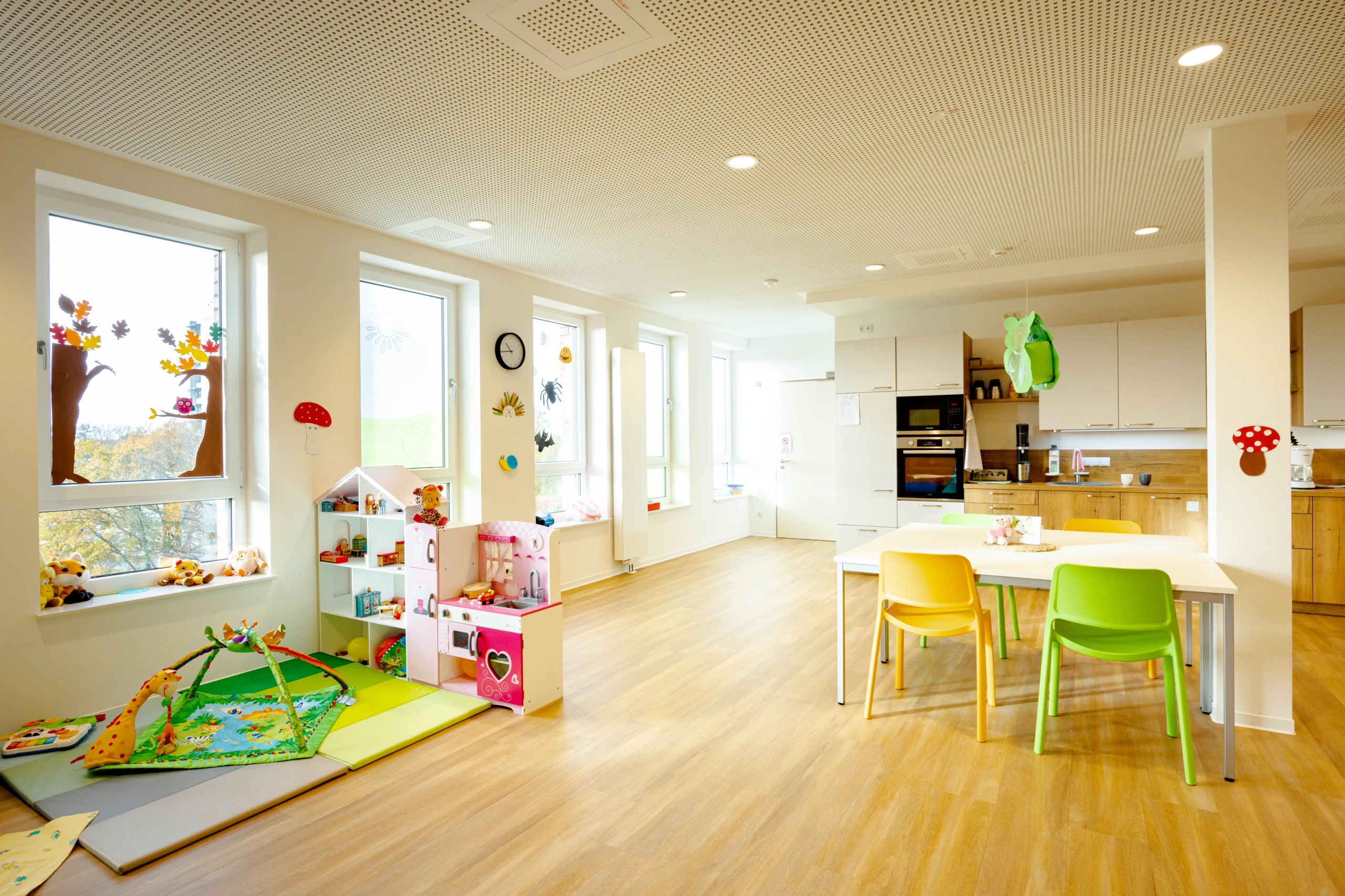 Großer, heller Raum mit Spielbereich für Kinder, Esstisch und integrierter Küchenzeile.