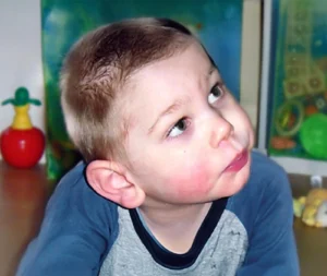 Kleines Kind sitzt im Spielumfeld und blickt aufmerksam zur Seite