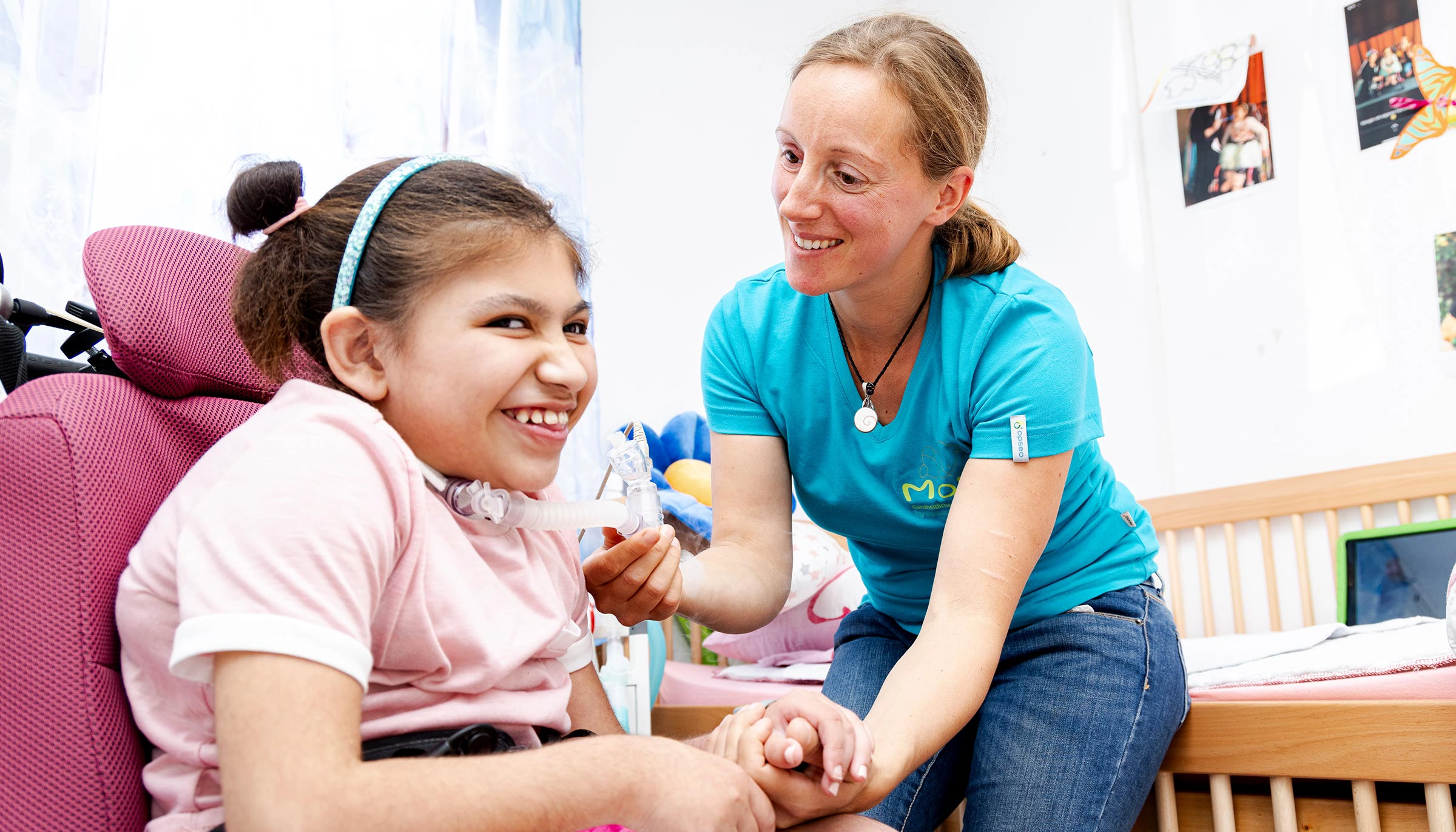 Pflegefachkraft betreut beatmetes Kind in vertrauter Umgebung