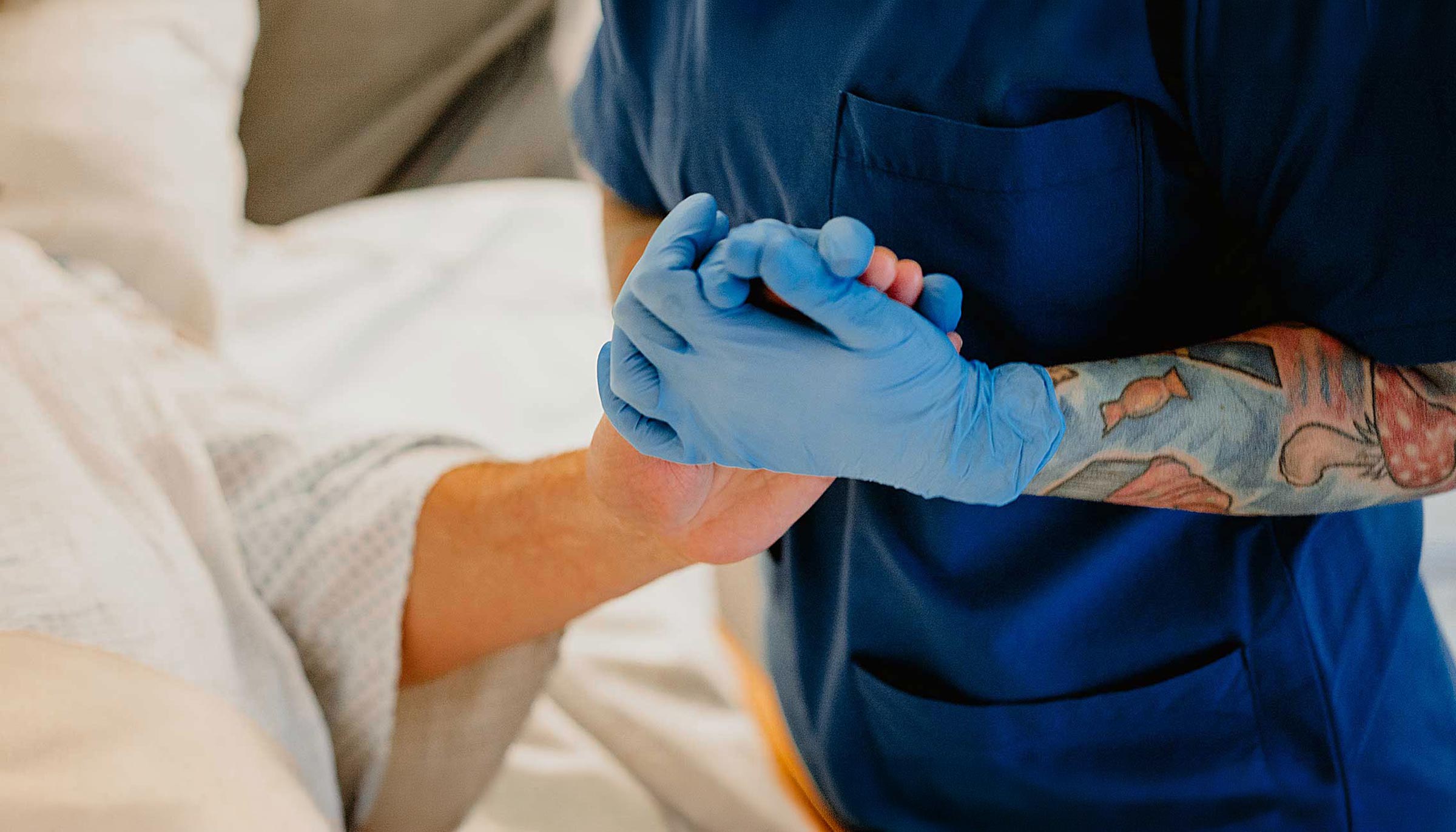 Pflegekraft hält Hand einer Patient:in