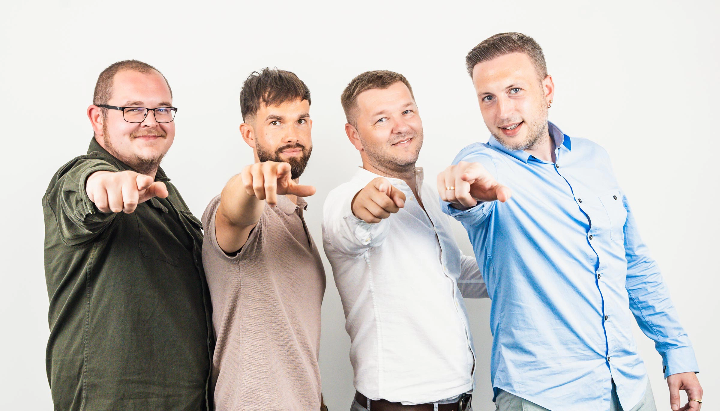 Mitarbeitende eines Pflegedienstes zeigen geschlossen in die Kamera