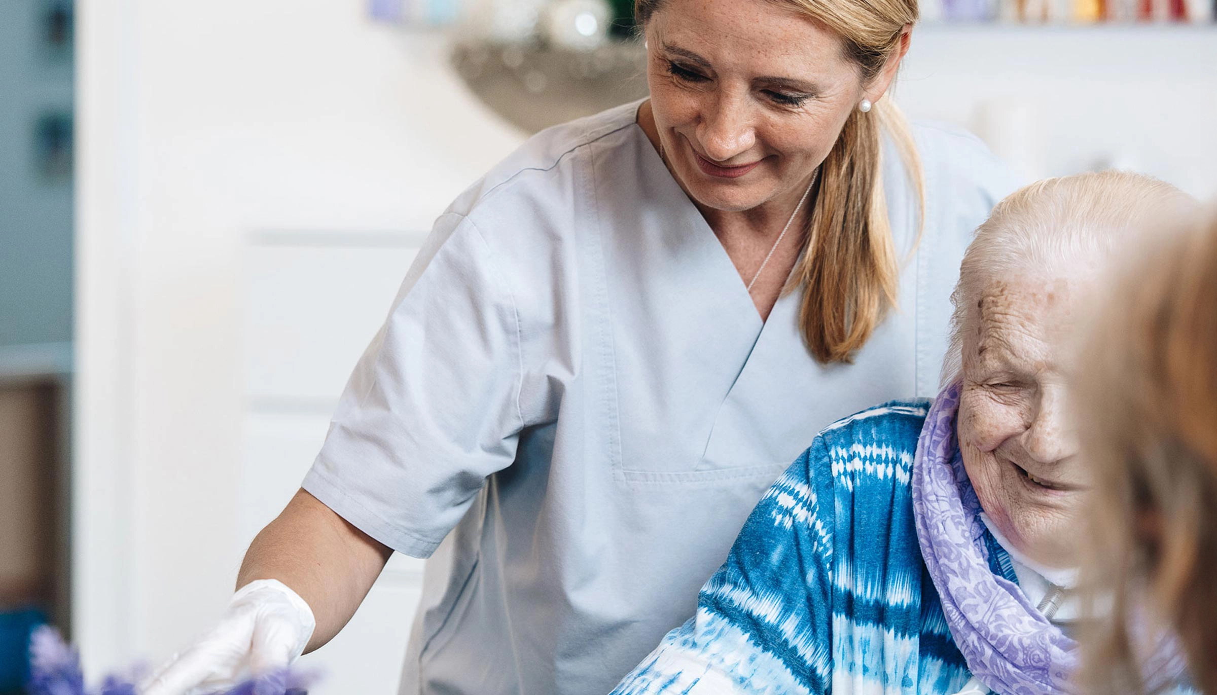 Pflegefachkraft betreut Seniorin mit Trachealkanüle im häuslichen Umfeld